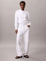 Buzo con capucha Calvin Klein de corte cropped, confeccionado en tejido de algodón y poliéster. Presenta un diseño minimalista en color blanco con el logotipo de la marca bordado en pequeño en el pecho y cordones ajustables en la capucha.