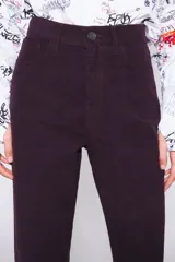 Pantalón de pana color borgoña, de corte recto, largo tobillero y tiro alto con cinco bolsillos. Cierre con cremallera y trabilla para el cinturón.