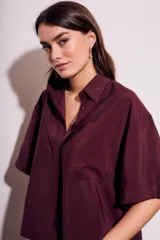 Camisa oversize color borgoña de mangas cortas con puños doblados y bolsillo en el pecho.