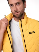 Chaleco acolchado color amarillo con diseño chevron, cuello alto, cierre frontal negro y parche con el logo de la marca en el pecho.
