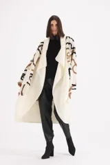 Spolverino largo de tejido de punto en color crudo, con diseño de patrones geométricos en tonos marrón y negro. Presenta un corte abierto con solapas amplias y mangas largas.