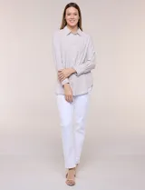 Camisa de calce relajado color celeste, confeccionada en tejido de textura suave y fluida. Presenta cuello camisero y abotonadura frontal, mangas largas con puño ancho y ruedo curvo.