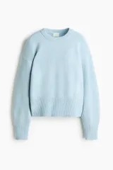 Buzo oversized celeste de punto suave levemente cepillado, con cuello redondo, hombros caídos y ribetes acanalados en puños y bajo.
