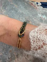 Pulsera de oro de 18k con diseño de cadena tipo serpiente doble y un nudo central decorativo. Cuenta con cierre de mosquetón y cadena de alargue con placa grabada.