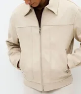 Campera estilo Harrington de corte bomber, confeccionada en material con acabado de gamuza sintética. Presenta cuello con solapa, cierre frontal completo, mangas largas y bolsillos laterales con cierre.