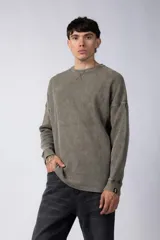 Buzo de corte oversize confeccionado en tela waffle de algodón con proceso de teñido acid wash. Presenta cuello redondo con detalle de costura en X y mangas largas con puños acanalados.
