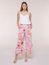 Pantalón de lino estilo crop y wide leg, de color rosado y blanco con estampado botánico en tonos rojizos. Cuenta con pretina trasera elastizada y bolsillos delanteros.