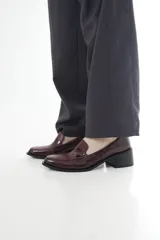 Mocasines Emilia de cuero vacuno en color bordó, con diseño de punta almendrada, detalle de antifaz con textura texturizada en la parte superior y tacón de bloque ancho en color negro.