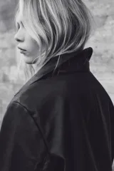 Campera corta negra de efecto cuero, con cuello camisero, cierre frontal de botones y dos bolsillos parche grandes en el frente.