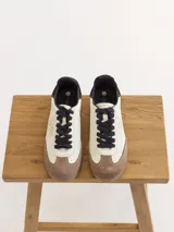 Championes de cuero color blanco con puntera y talón en cuero color marrón. Cordones negros y logo bordado en tonos metálicos en el lateral. Diseñados en Uruguay y producidos en Colombia.