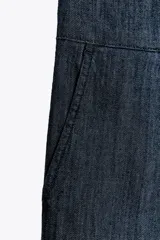 Pantalón culotte de denim azul oscuro, tiro medio, con cintura elástica en la parte trasera, bolsillos laterales y pinzas delanteras. Cierre frontal con cremallera, botón y ganchos metálicos.