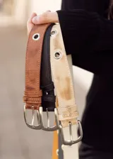 Cinto de cuero color marrón, negro y beige con hebilla metálica plateada y ojales metálicos.