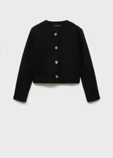 Chaqueta de tejido bouclé en color negro con textura y detalles brillantes. Presenta un diseño recto, cuello redondo, manga larga, cierre frontal con botones efecto joya y dos bolsillos de parche delanteros.