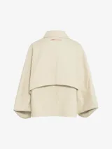 Chaqueta corta color beige, de cuello estilo camisa, con cierre de botones oculto, mangas murciélago y bolsillos con solapa.