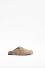 Zueco de cuero vacuno color beige, con diseño de punta cerrada, ajuste mediante hebilla metálica lateral y suela de corcho con base de goma.