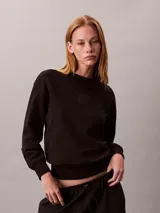 Buzo de felpa Calvin Klein de color negro, corte regular y cuello redondo, con el nuevo emblema con logo texturizado en el pecho y puños, cuello y bajo de canalé.