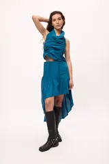 Falda azul con corte irregular, más corta en el frente y más larga en la parte trasera. Presenta volados en la parte inferior y frunces en la cintura.