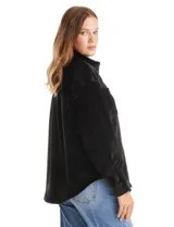 Sobrecamisa de pana con textura acanalada, corte oversize y silueta holgada. Presenta cuello clásico, cierre frontal con botones metálicos, mangas largas con puños abotonados y dos bolsillos frontales tipo parche con solapa.