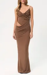 Vestido largo color marrón, de corte ajustado, con escote drapeado y tirantes finos. Presenta un diseño con abertura lateral en la cintura y detalle de fruncido en la falda.