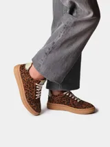 Zapatillas de cuero con estampado animal print tipo leopardo, cordones blancos y suela plana de goma.