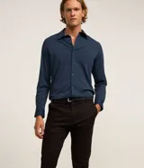 Pantalón slim de sarga color negro, con cierre de botón y cremallera, y bolsillos funcionales.