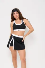 Conjunto deportivo compuesto por un top y una pollera short. El top es de estilo deportivo con cuello redondo y ribetes blancos en contraste. La pollera short cuenta con un diseño de tajo lateral con borde blanco y cintura elástica a juego.