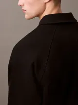 Sweater negro de Calvin Klein con cuello tipo chomba, cierre de cremallera parcial y logo "CK" bordado en blanco en el pecho.