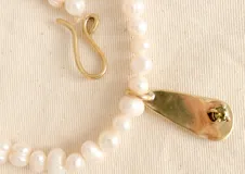 Gargantilla de perlas de río con dije dorado en forma de gota.