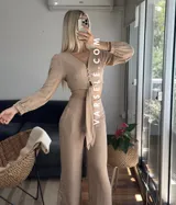 Conjunto color beige compuesto por un top corto con escote en V, botones frontales y mangas largas abullonadas con puños elásticos, y un pantalón de tiro alto con lazo en la cintura.