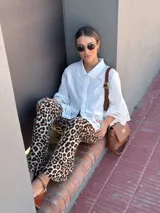 Cartera tipo bandolera de cuero color tostado, con solapa frontal, cierre principal y herrajes metálicos. Incluye dos correas desmontables, una corta para llevar al hombro y una larga ajustable para usar cruzada.