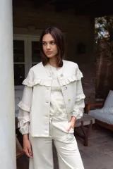 Campera de jean blanca con volados en el frente y las mangas, confeccionada en algodón y lino.