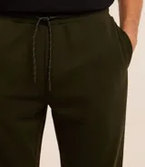 Pantalón tipo jogger de corte holgado, color verde oliva, con cintura elástica ajustable mediante cordón, bolsillos laterales y puños elásticos en los tobillos.