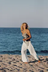 Pantalón de tiro medio confeccionado en tejido satinado blanco, con cintura elástica, diseño plisado y bajo abullonado y asimétrico.