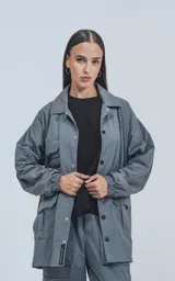 Campera técnica de media estación con calce oversize, confeccionada en microfibra liviana de secado rápido. Presenta diseño funcional tipo piloto y rompevientos, forrada con red, con cuello camisero, cierre frontal con botones a presión y cuatro bolsillos delanteros.