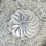 Broche con forma de flor color verde oliva, realizado artesanalmente en Italia con pétalos de cuero superpuestos. Se aplica con imán.