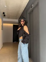 Blusa de manga larga y hombros descubiertos de color negro, con diseño halter fruncido en el cuello y mangas abullonadas caídas.
