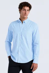 Camisa de manga larga confeccionada en popelina con estampado de rayas verticales en tonos celeste y blanco, cuello con botones y bolsillo aplicado en el pecho.