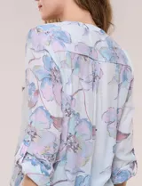 Blusa Hope & Harlow de gasa estampada con patrón floral en tonos azul y blanco, escote en V con botones frontales, mangas largas regulables y nudo decorativo en el ruedo.