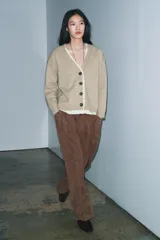 Chaqueta tipo cárdigan de lana en color beige, con diseño de tejido combinado que incluye una capa interior de tela clara. Presenta escote en pico, manga larga y cierre frontal con botones oscuros.