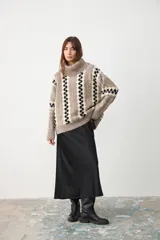 Sweater de punto con cuello tortuga, diseño holgado y estampado de rayas verticales con patrón geométrico en tonos beige, marrón y negro.