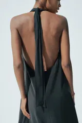 Vestido midi negro de tejido fluido, con cuello halter que se anuda en la nuca y escote pronunciado en pico.