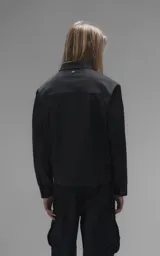 Chaqueta de corte regular crop confeccionada en microfibra pesada levemente elastizada. Presenta un diseño inspirado en la campera de jean clásica, con cuello volcado, cierre frontal mediante broches snap a tono y dos bolsillos delanteros con solapa.