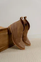 Botas cortas de estilo western confeccionadas en cuero, con puntera y talón texturizados con diseño de reptil y paneles laterales de gamuza. Presentan cierre lateral, tirador en la parte superior y taco bajo de madera.