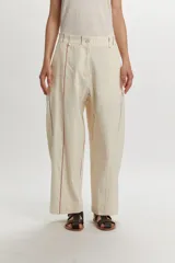 Pantalón de corte relajado, color beige, con diseño de rayas sutiles verticales y líneas de colores en contraste. Presenta cierre frontal con botón y trabillas para cinturón.