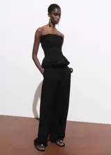 Pantalón de tiro medio color negro, con diseño recto y largo, trabillas en la cintura y dos bolsillos laterales. Cuenta con cierre oculto de botón, gancho y cremallera.