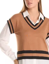 Buzo combinado de estilo preppy que simula un conjunto de sweater tejido con camisa debajo. Presenta un cuerpo de punto color marrón con escote en V y ribetes negros en cuello, sisas y ruedo, integrado con cuello, mangas largas y bajo de gasa blanca.