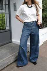 Jean wide leg de tiro medio, color azul, con cortes diagonales y estampa de flor en los bolsillos traseros.