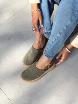 Zuecos de cuero color verde seco, con hebilla lateral y suela de goma.