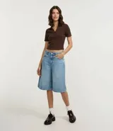 Blusa de manga corta confeccionada en tejido rib de algodón con elastano. Presenta cuello polo con escote en V y diseño ajustado al cuerpo.