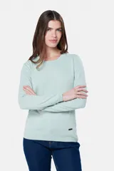 Buzo tejido en hilo de algodón color beige, con cuello redondo y manga larga. Presenta un corte clásico y un pequeño detalle metálico en la parte inferior izquierda.